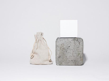 a small hessian bag on the left, and a square concrete block with a white card on top