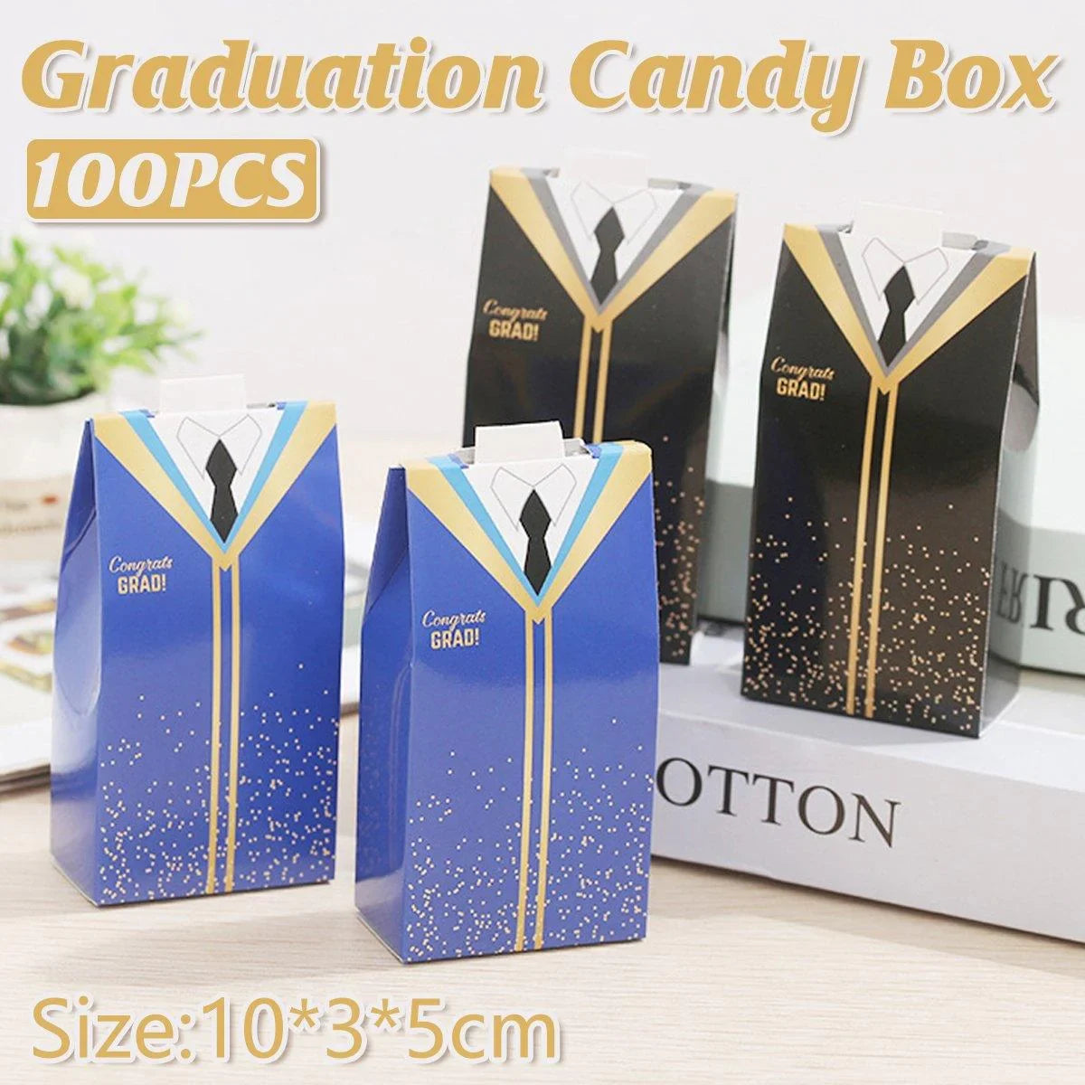 A festive setup of graduation candy boxes in a scenic outdoor location, with a sign reading "100PCS" and product dimensions labeled.