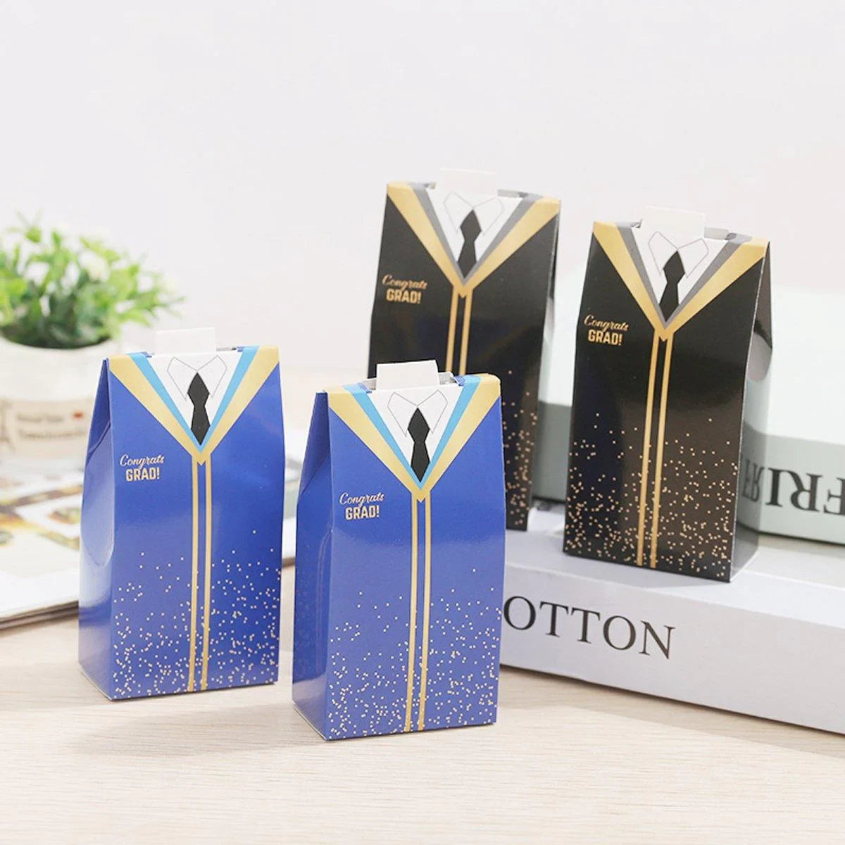 Multiple graduation candy boxes with a mix of black and blue gowns, each featuring a tie.