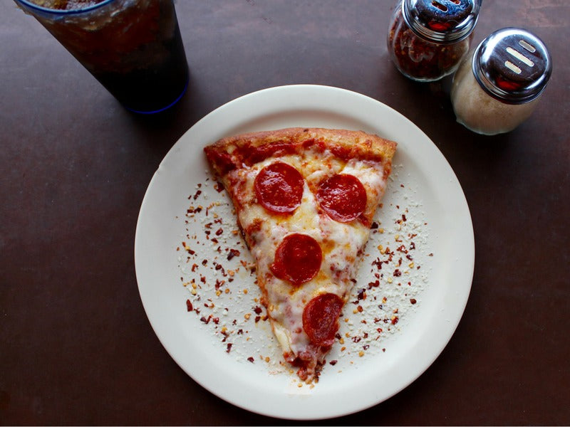 A slice of pepperoni pizza on a white plate