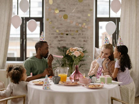A family wearing party hats celebrates a birthday at a decorated table