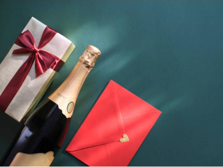 A champagne bottle, a gift box with a red ribbon, and a red envelope with a heart-shaped seal