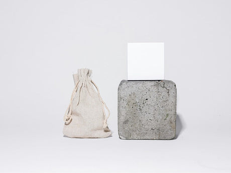  a small hessian bag on the left, and a square concrete block with a white card on top