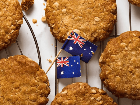 ANZAC biscuits are cooling on a wire rack, with small Australian flags placed among them