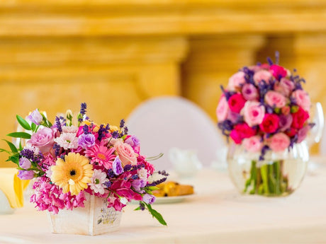 a beautifully decorated table with vibrant floral arrangements, featuring colorful roses, daisies, and lavender in elegant vases