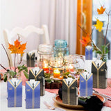 A festive party table with fall decorations and graduation gown-shaped candy boxes.
